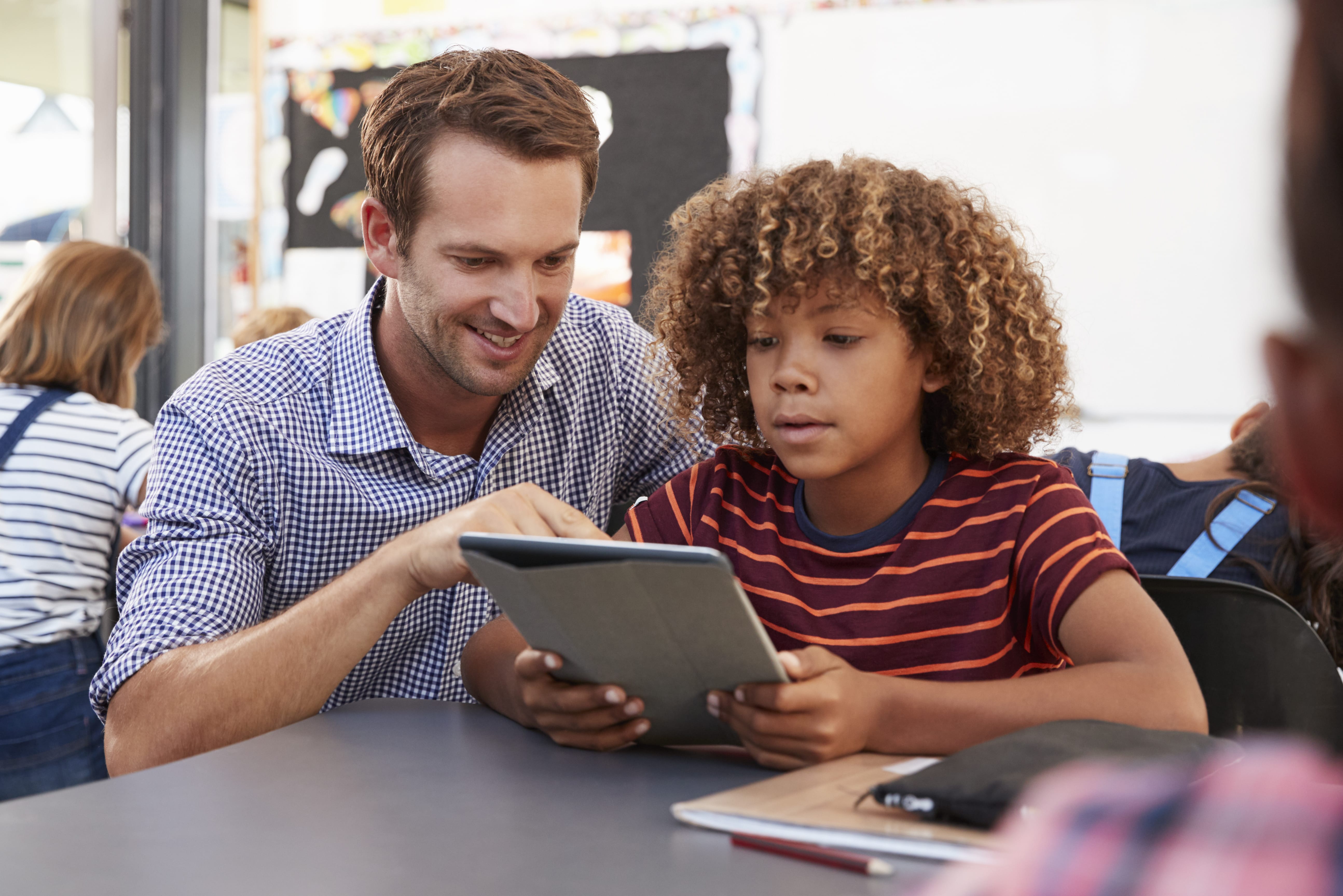 male teacher and African American elementary school student looking at a tablet