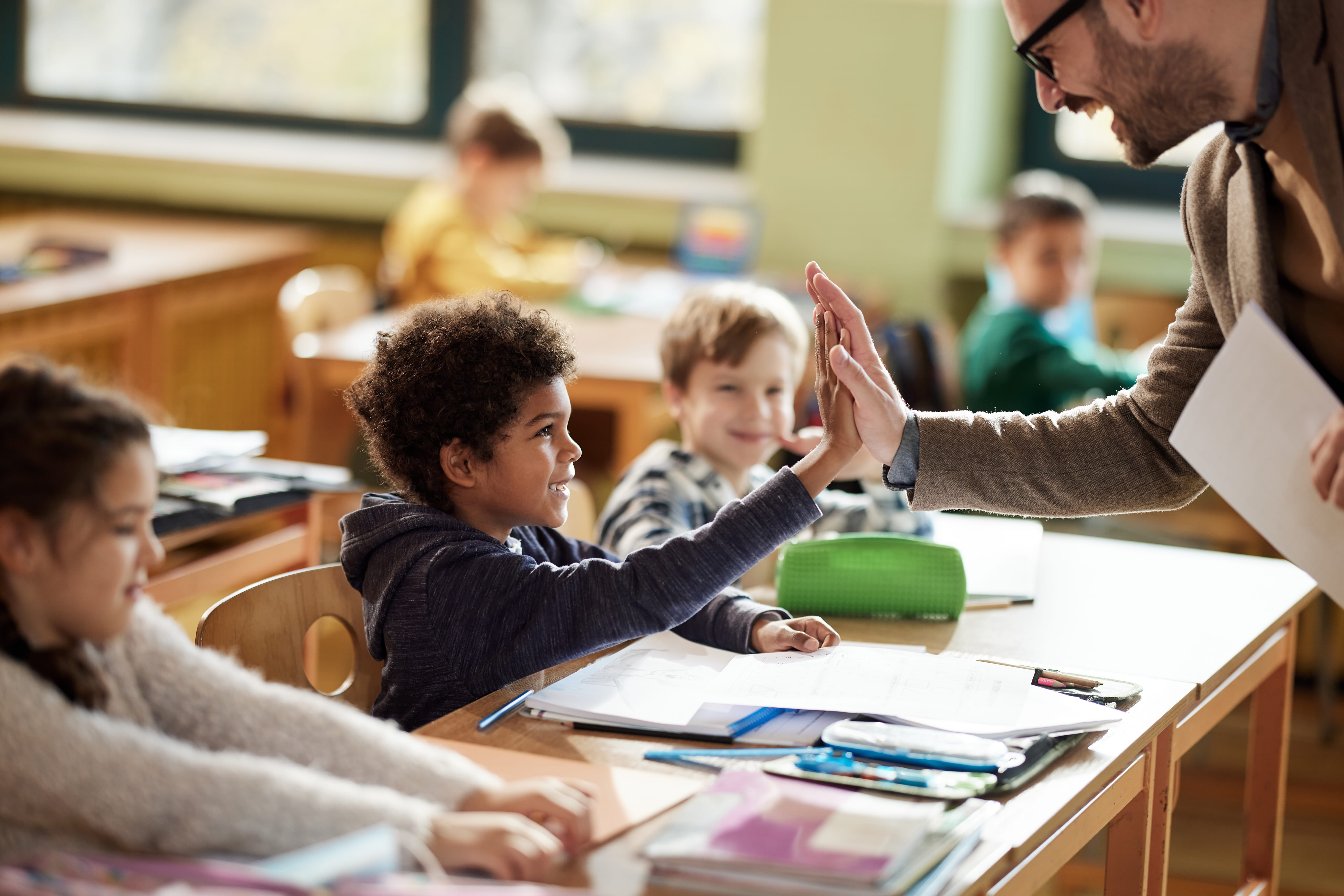 Male teacher high-fiving an elementary school student for successfully completing a classroom routine like Eduprotocols and Project Zero thinking routines.