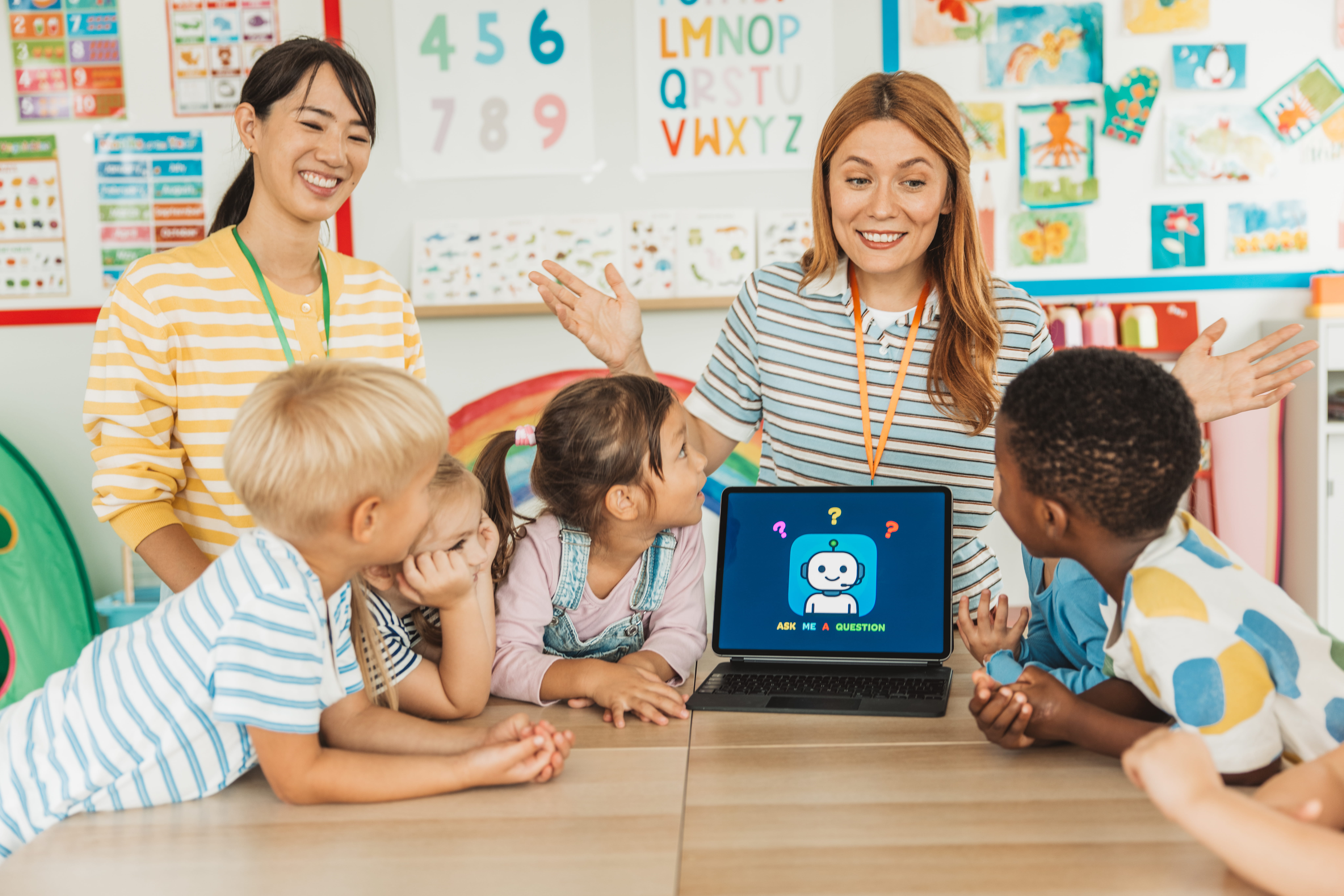 Two teachers using a laptop to show four young elementary school students an interactive activity they created with SchoolAI.